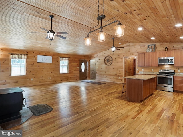 79 Whiskey Still Rd, Berkeley Springs, WV 25411 - kitchen with appliances with stainless steel finishes, a ceiling fan, a wood stove, open floor plan, and wooden walls