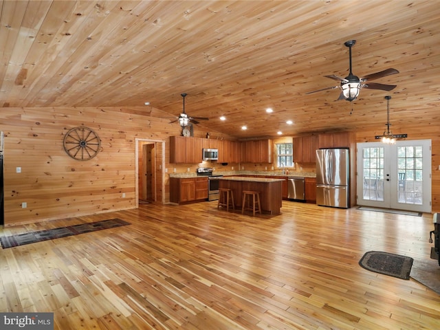 79 Whiskey Still Rd, Berkeley Springs, WV 25411 - kitchen featuring appliances with stainless steel finishes, ceiling fan, brown cabinetry, light wood finished floors, and wooden walls