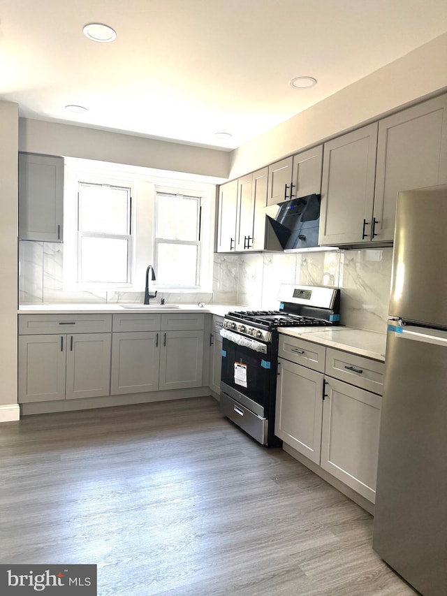 6529 Vandike St, Philadelphia, PA 19135 - kitchen featuring stainless steel appliances, a sink, gray cabinets, range hood, and tasteful backsplash