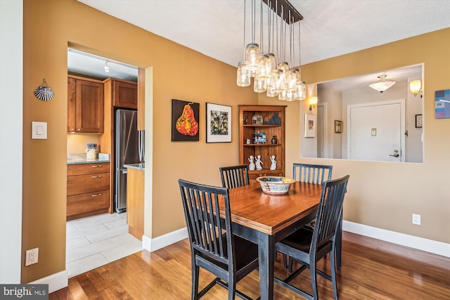 dining space featuring light wood-type flooring, baseboards, and a chandelier