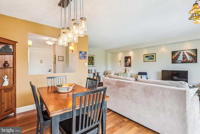 dining room featuring wood finished floors, a chandelier, and baseboards