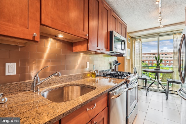 kitchen featuring appliances with stainless steel finishes, a sink, decorative backsplash, brown cabinets, and floor to ceiling windows