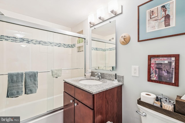 full bath with toilet, vanity, and shower / bath combination with glass door