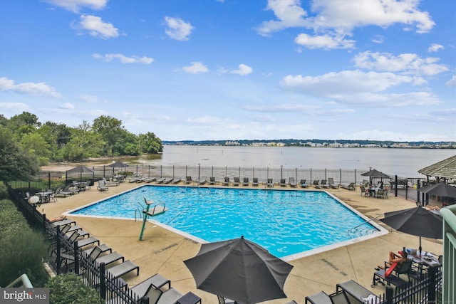 community pool with fence, a patio area, and a water view