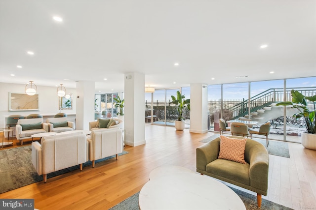 living area featuring light wood finished floors, recessed lighting, and a wall of windows
