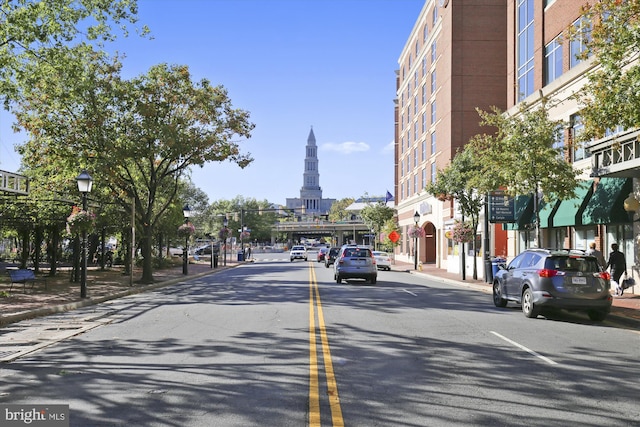 view of asphalt road with street lights, curbs, and sidewalks