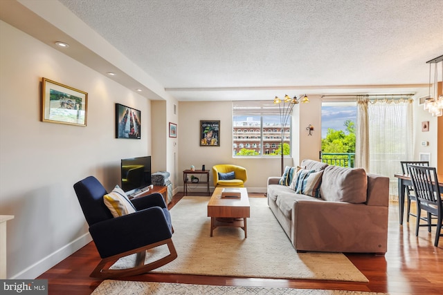 living room featuring a textured ceiling, a chandelier, baseboards, wood finished floors, and recessed lighting