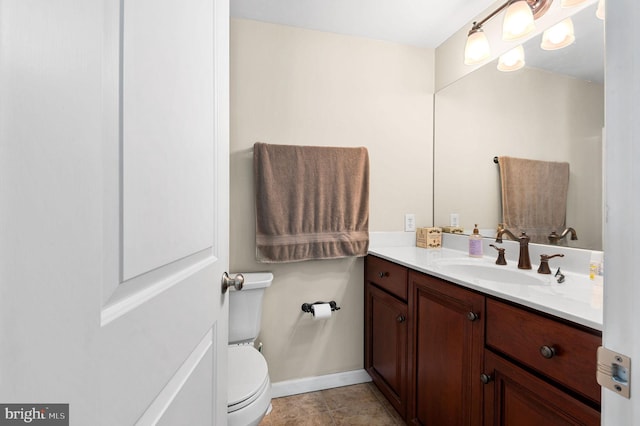 half bath with toilet, vanity, and baseboards