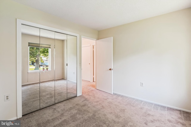 unfurnished bedroom with carpet floors, a closet, and baseboards