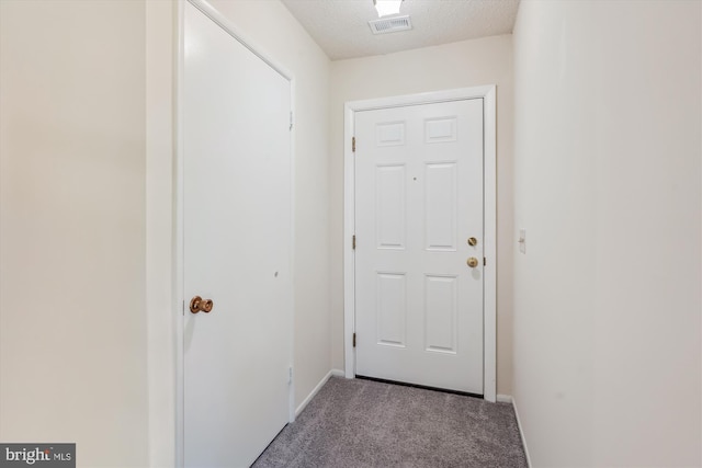 entryway featuring carpet flooring, baseboards, and a textured ceiling