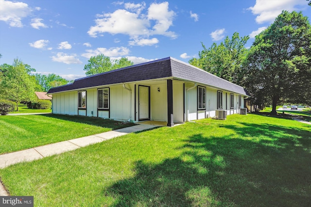 view of front facade featuring a front yard, mansard roof, a shingled roof, and central air condition unit