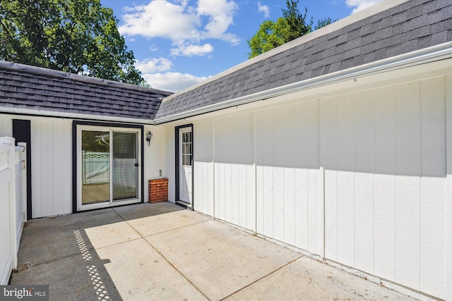 entrance to property with roof with shingles, mansard roof, and a patio area