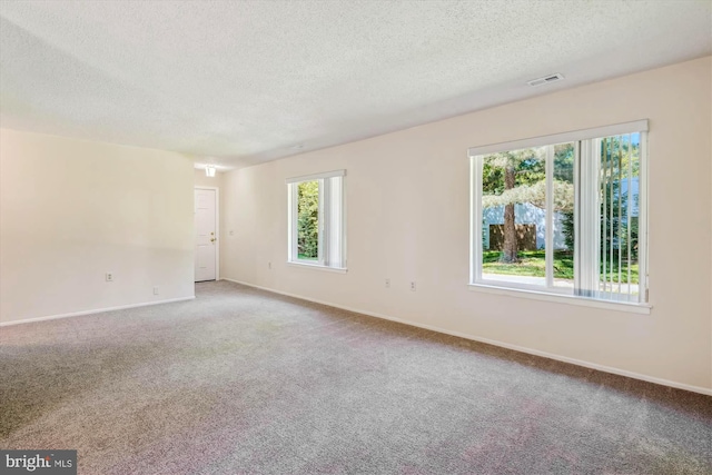 spare room with a textured ceiling, light colored carpet, and baseboards