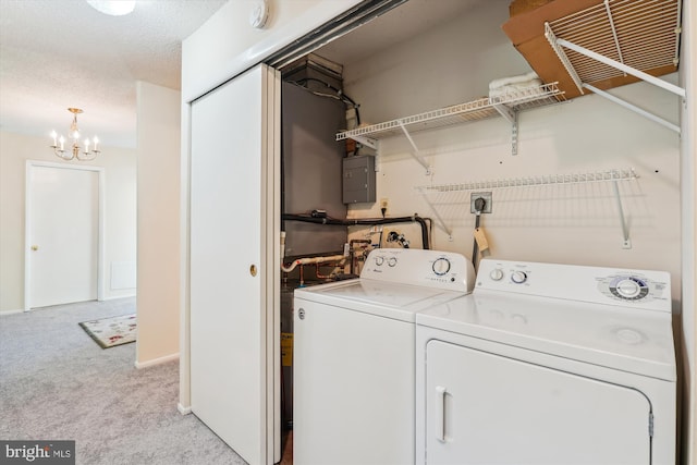 laundry area with washing machine and clothes dryer, a chandelier, light colored carpet, and electric panel