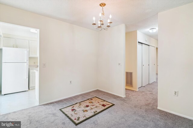 unfurnished room featuring light carpet, a chandelier, baseboards, and a textured ceiling