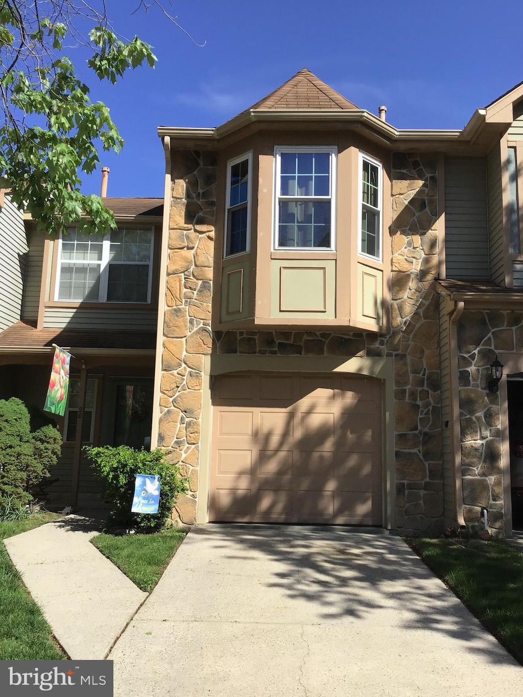 view of front facade with stone siding, a garage, and concrete driveway