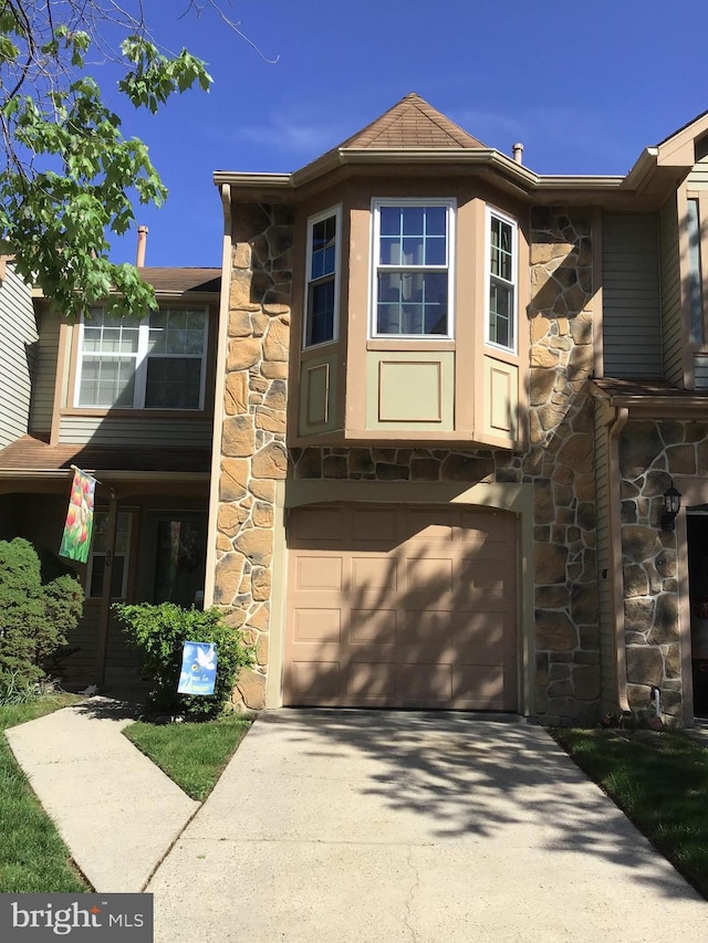view of front facade with stone siding, a garage, and concrete driveway