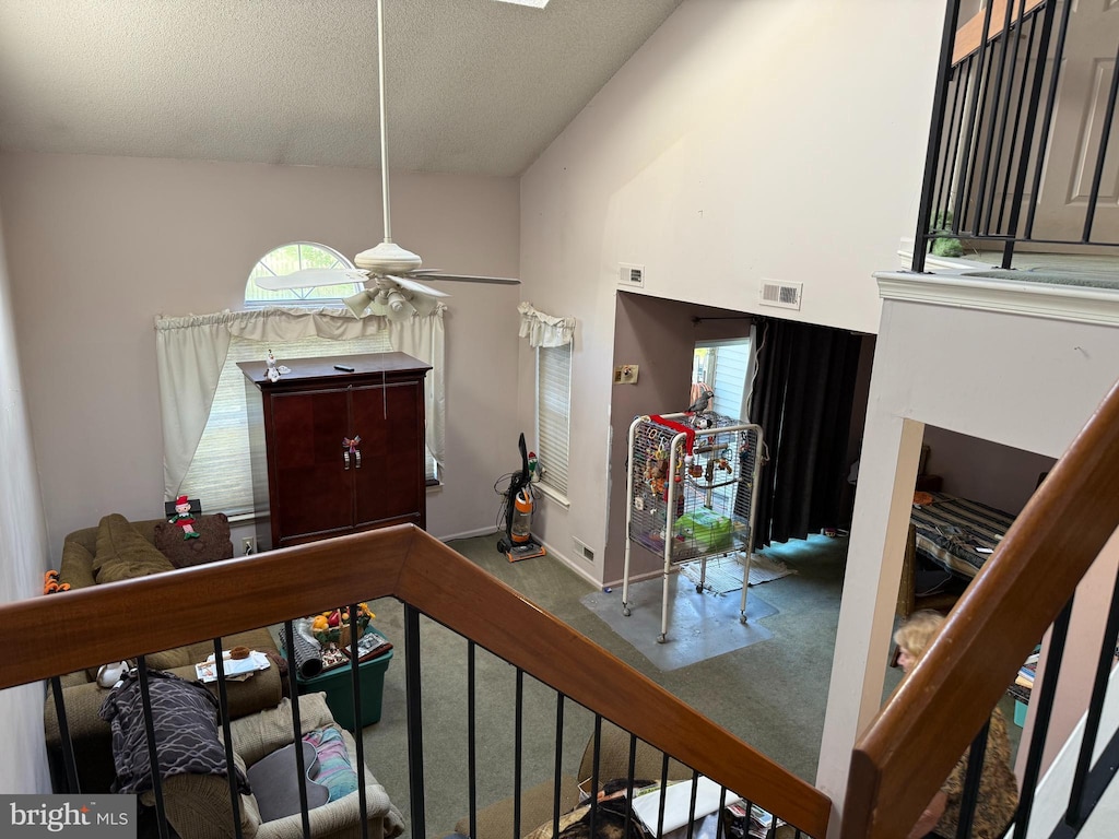 carpeted entryway with a ceiling fan, a textured ceiling, and vaulted ceiling