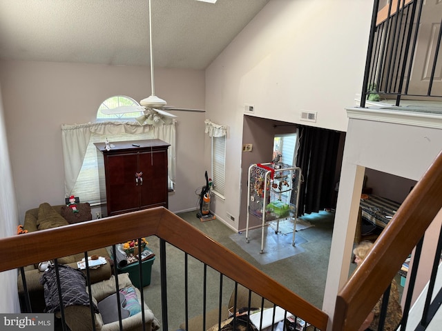 carpeted entryway with a ceiling fan, a textured ceiling, and vaulted ceiling
