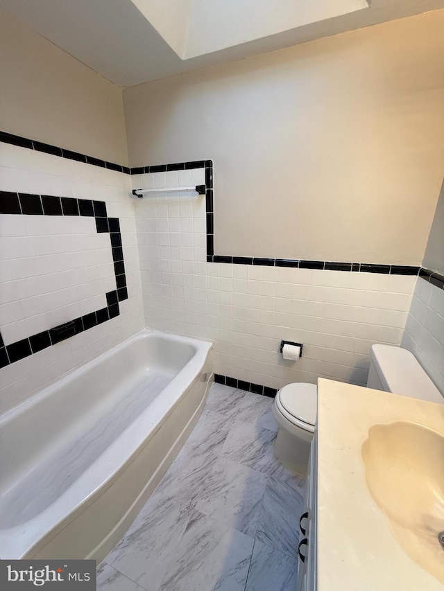 426 S Church St, Clifton Heights, PA 19018 - bathroom featuring toilet, a tub, tile walls, vanity, and marble look tile flooring