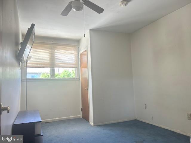 carpeted empty room featuring baseboards, a ceiling fan, and a smoke detector