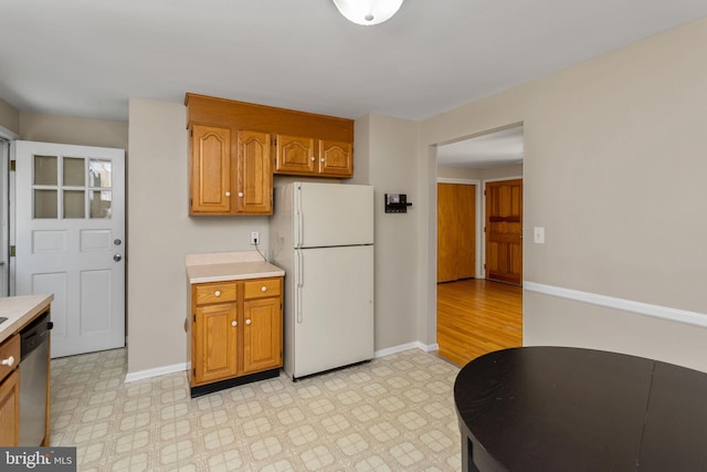 kitchen with freestanding refrigerator, light countertops, light flooring, brown cabinets, and dishwasher