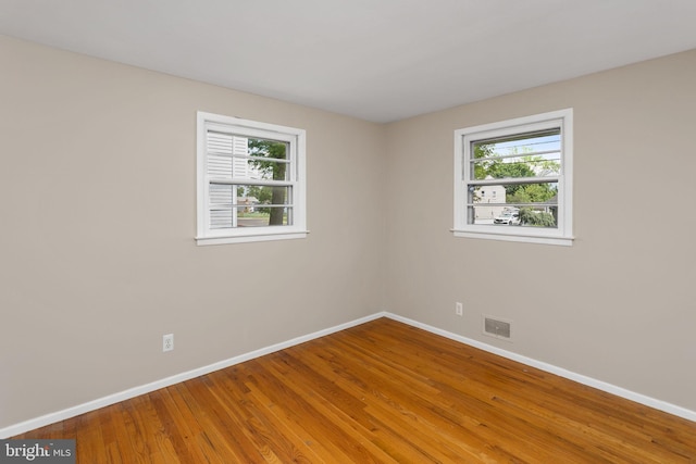 spare room with baseboards, healthy amount of natural light, and wood finished floors