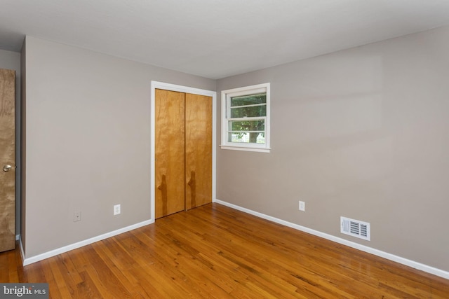unfurnished bedroom featuring baseboards, wood finished floors, and a closet
