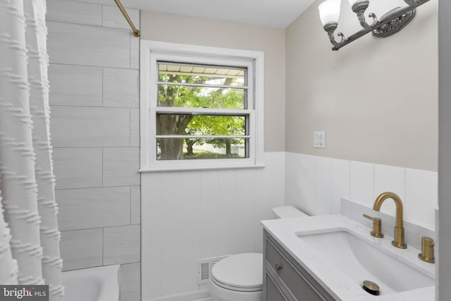 bathroom featuring toilet, vanity, shower / bath combo with shower curtain, and a wainscoted wall