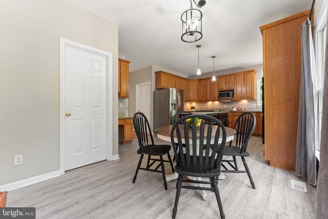 dining area featuring light wood-style flooring and baseboards