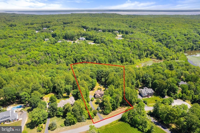 aerial view of property and surrounding area with a heavily wooded area, property parcel outlined, and a large body of water