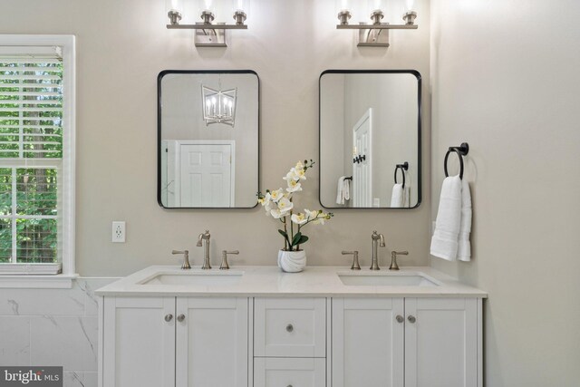 bathroom with double vanity and a chandelier