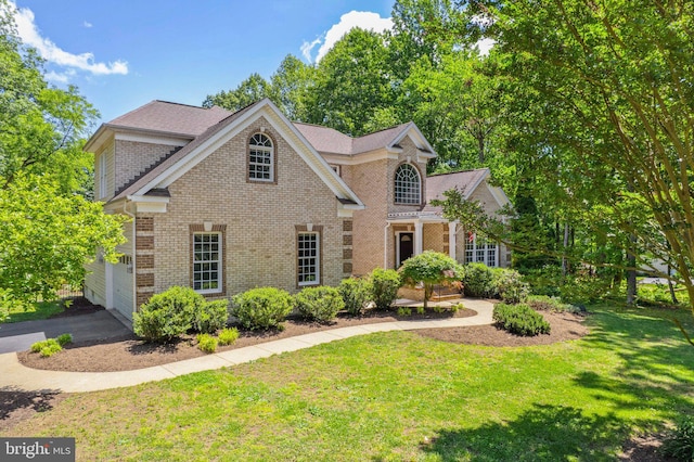 view of front of home featuring brick siding, a front lawn, and a garage