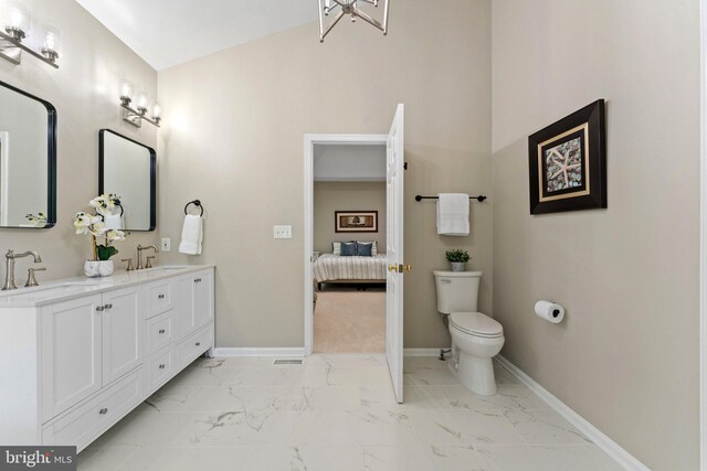 full bathroom with marble finish flooring, baseboards, toilet, and double vanity