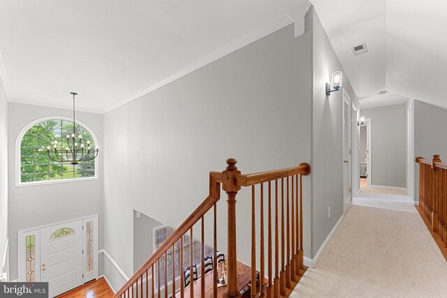 corridor featuring an upstairs landing, a chandelier, baseboards, and carpet flooring