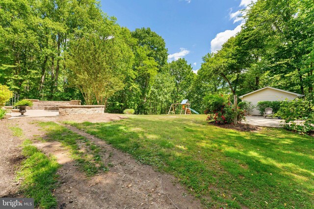 view of grassy yard featuring a playground and a patio