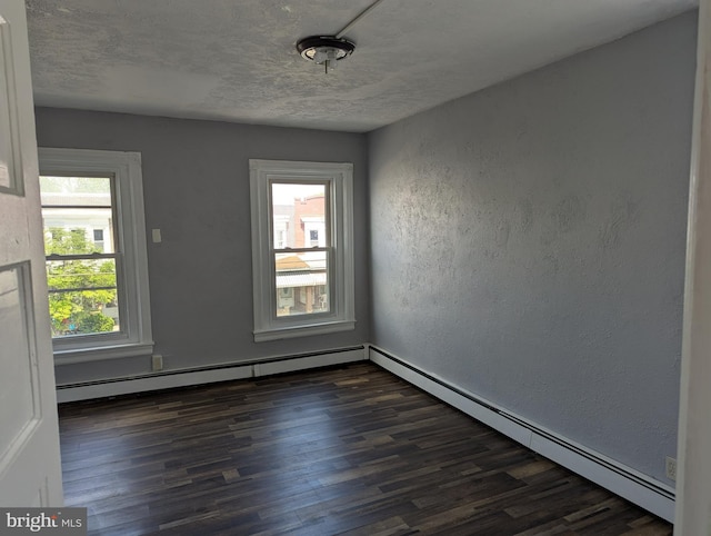 spare room with dark wood-style flooring, healthy amount of natural light, a textured wall, baseboard heating, and a baseboard heating unit