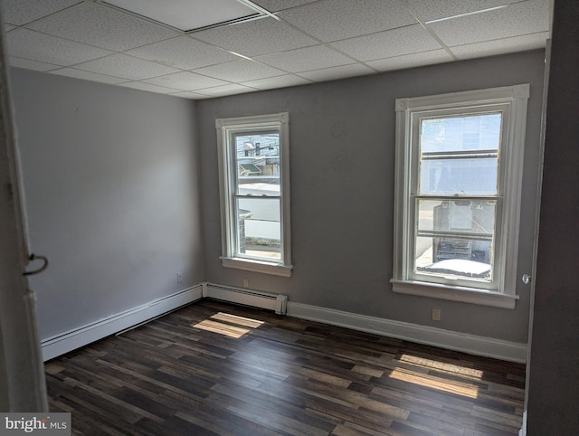 unfurnished room with a drop ceiling, dark wood-style floors, baseboards, and a baseboard heating unit