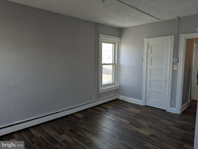 unfurnished room with a baseboard heating unit, dark wood finished floors, baseboards, a textured ceiling, and a textured wall