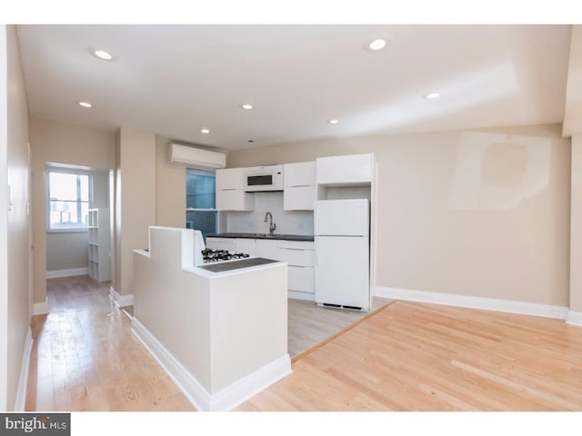 1539 E Berks St, Philadelphia, PA 19125 - kitchen with white appliances, a sink, white cabinetry, an AC wall unit, and light wood-style floors