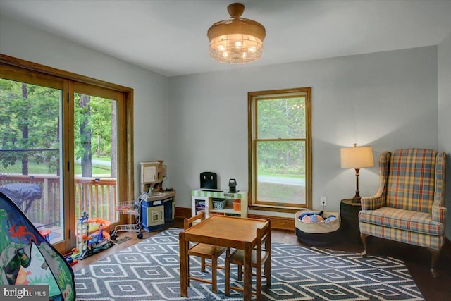 rec room featuring healthy amount of natural light, a chandelier, and wood finished floors