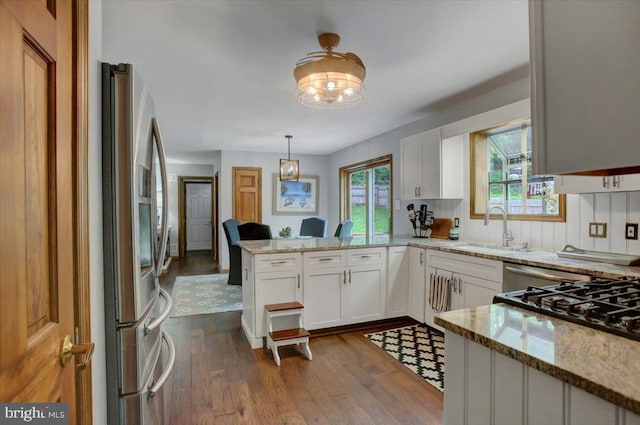 kitchen featuring a sink, stainless steel fridge, a peninsula, and light stone counters