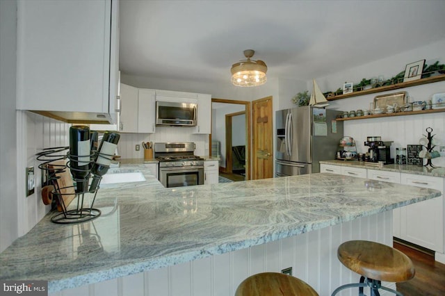 kitchen with appliances with stainless steel finishes, light stone countertops, white cabinets, and open shelves