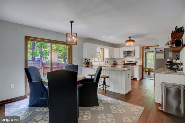 dining area with dark wood-style flooring, baseboards, and a chandelier