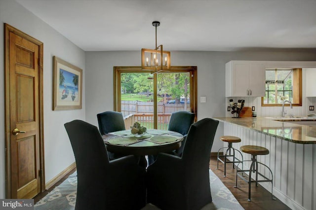 dining room featuring a chandelier, dark wood-style flooring, and baseboards