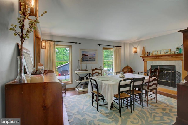 dining space with healthy amount of natural light, wood finished floors, a fireplace, and baseboards