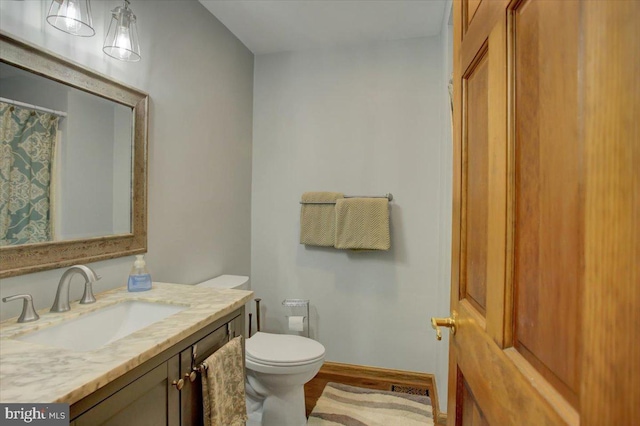 bathroom with toilet, vanity, and wood finished floors