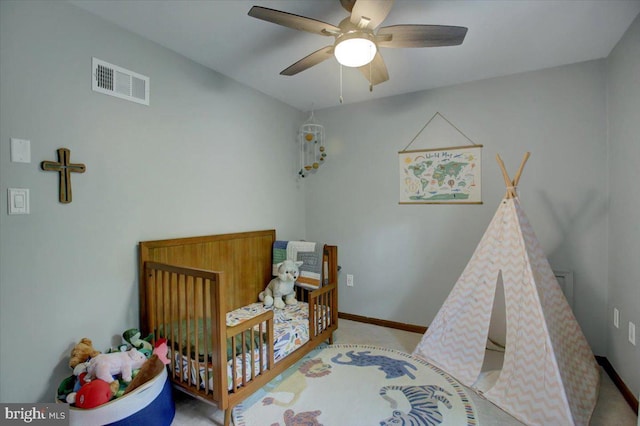 bedroom featuring a crib, a ceiling fan, and baseboards