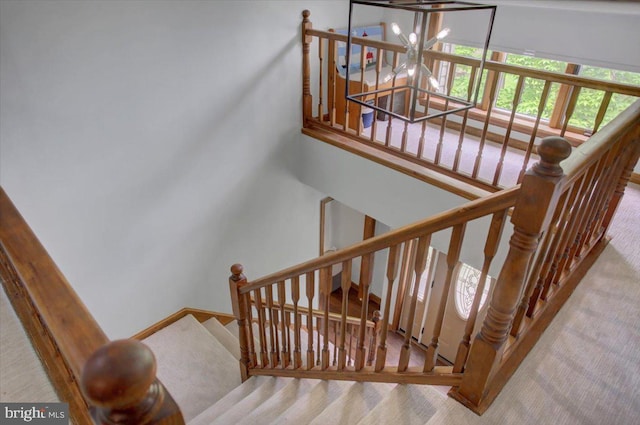 staircase featuring carpet floors, a chandelier, and baseboards