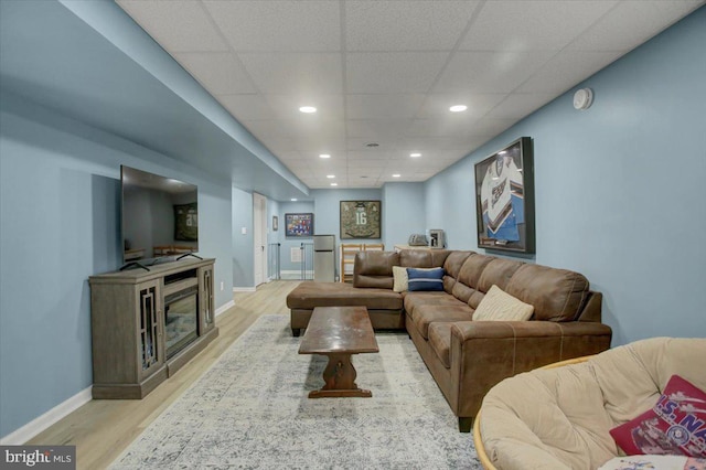 living area featuring light wood-style flooring, baseboards, recessed lighting, and a drop ceiling